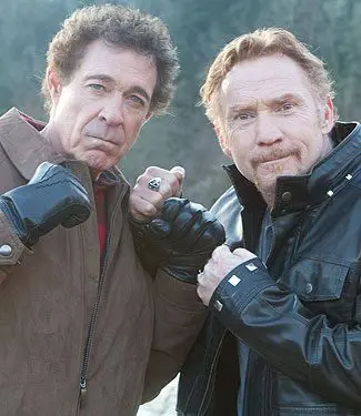 Two men in black leather jackets and gloves.