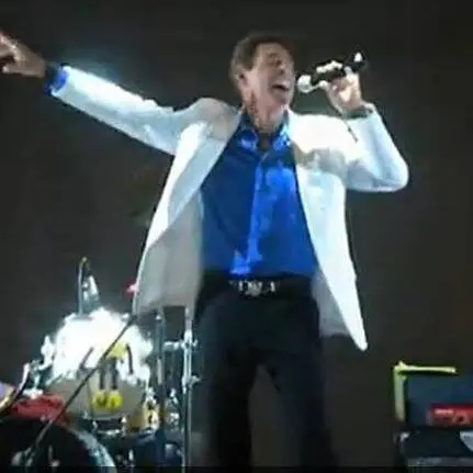 A man in white jacket holding a microphone.