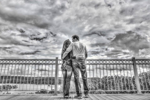 A man and woman standing on the side of a bridge.