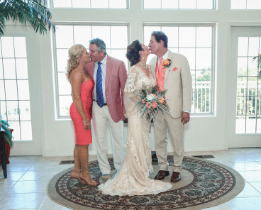 A bride and groom kiss in front of their family.